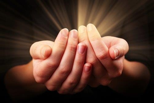 Hands cupped together with a bright glowing light being emitted from the palms.